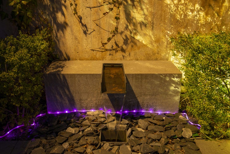 Beleuchteter Gartenbrunnen mit Steinumrandung und Bepflanzung