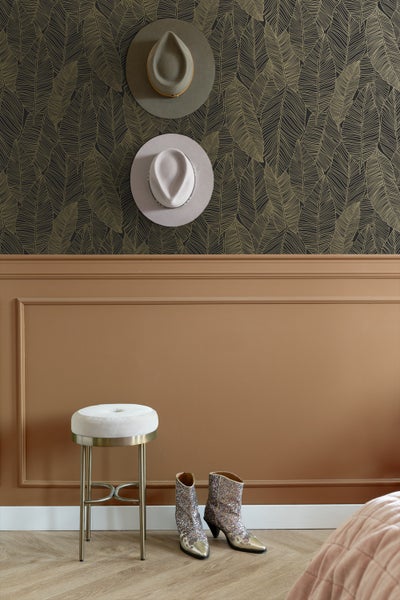 Zimmeransicht mit zwei Hüten an der Wand, einem Hocker und einem Paar Stiefel.