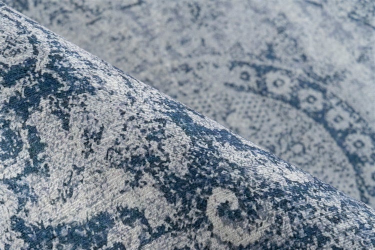 Nahaufnahme eines strukturierten Teppichs mit blauem und grauem Vintage-Muster im Used-Look.