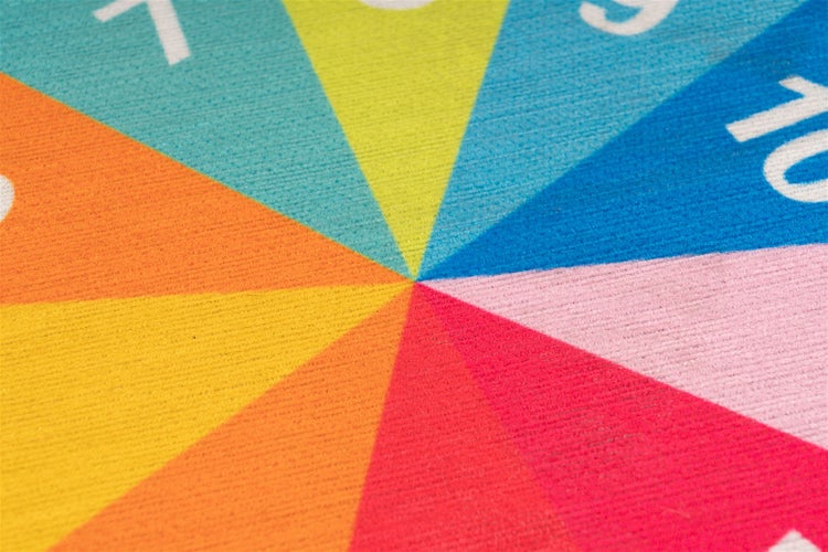 Detailansicht eines bunten runden Kinderteppichs mit nummerierten Segmenten, die von der Mitte ausgehen.