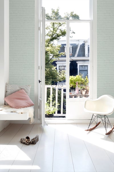 Heller Raum mit Ziegelmustertapete, Sitzgelegenheit am Fenster und Balkontür