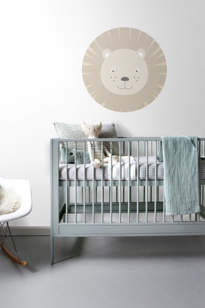 Babyzimmer mit Gitterbett, Kissen und Wandtattoo Löwe