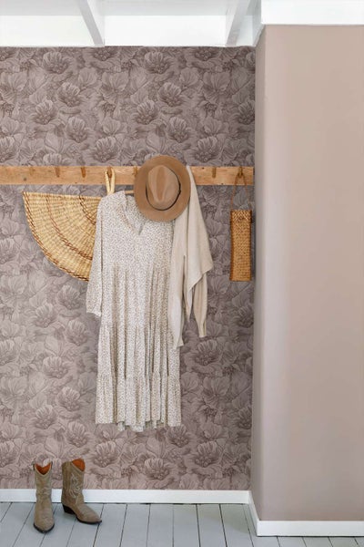 Modernes Badezimmer mit wandmontiertem Waschbecken, goldfarbener Armatur, ovalem Spiegel und florale Tapete über rechteckigen Wandfliesen.