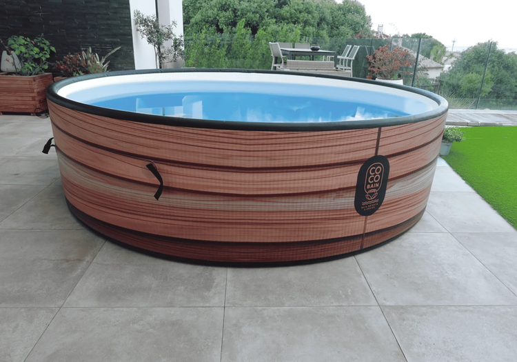 Aufblasbarer runder Whirlpool mit Außenwand in Holzoptik auf einer Terrasse mit Fliesenboden im Außenbereich.
