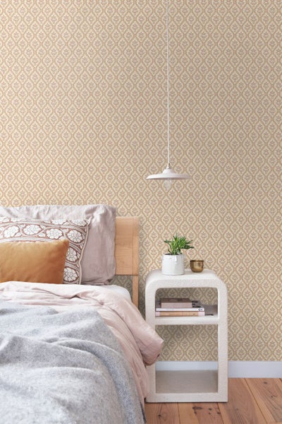 Schlafzimmer mit Vliestapete im geometrischen Blumenmuster, Holzbett, weißem Nachttisch und moderner Hängeleuchte.