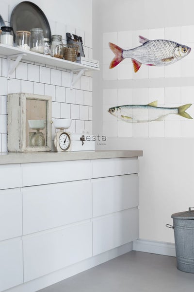 Helle Küche mit weißen Schränken, gefliesten Wänden und Fischmotiven