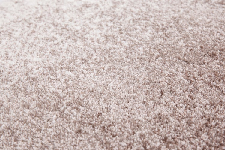 Detailaufnahme der weichen Struktur eines beigen Hochflor-Teppichs.