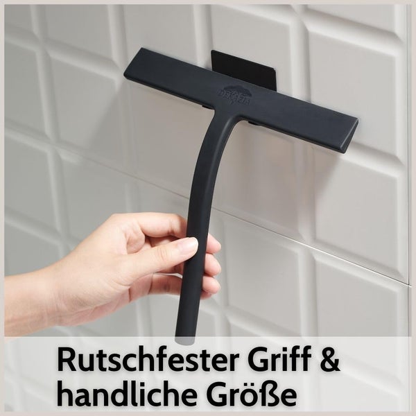 Dekazia Duschabzieher mit rutschfestem Griff in der Hand, aufgehängt an einer gefliesten Wand.