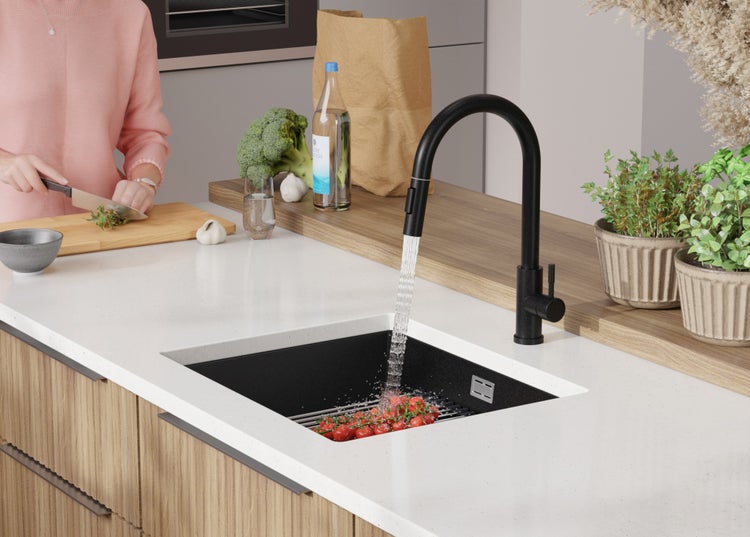 Küchenszene mit Spüle, Armatur und Person beim Gemüseschneiden