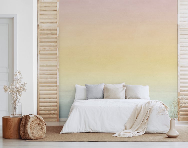 Schlafzimmer mit farbverlaufender Vliestapete, Bett und dekorativen Elementen.