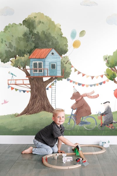 Wandbild mit Illustration eines Baums mit Baumhaus, Tieren auf Fahrrädern und spielendem Kind