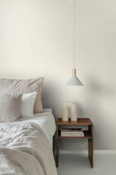 Schlafzimmer mit Bett, Nachttisch, Lampe und Tapete mit Schriftmuster