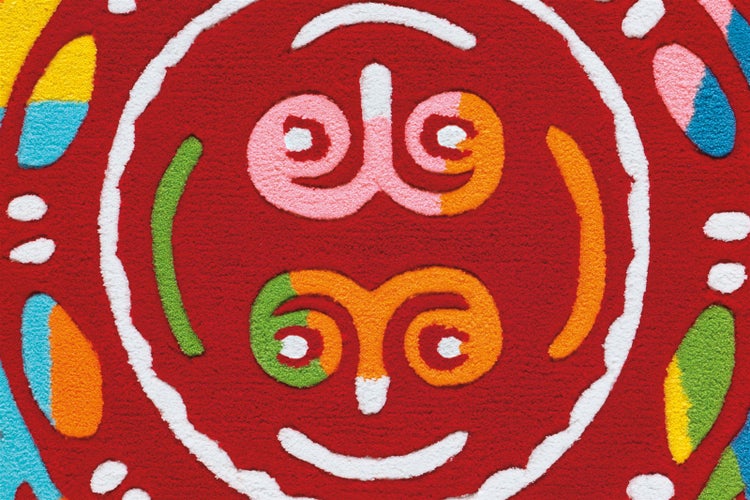 Nahaufnahme eines bunten Kinderteppichs mit weicher Textur und kreisförmigem Muster mit Wirbeln und einem Gesicht.