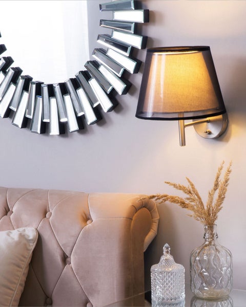 Szene mit Spiegel, Wandleuchte, Sofa und Dekoration auf einem Tisch