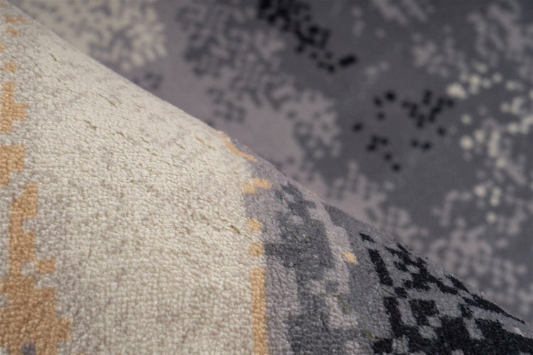 Detailaufnahme eines Teppichs mit abstraktem Pixelmuster und weicher Oberflächenstruktur.