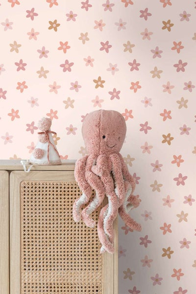 Kindertapete mit Blumenmuster vor einem Holzschrank mit Rattangeflecht, dekoriert mit einem Stoffoktopus und einer Partyhütchendekoration.