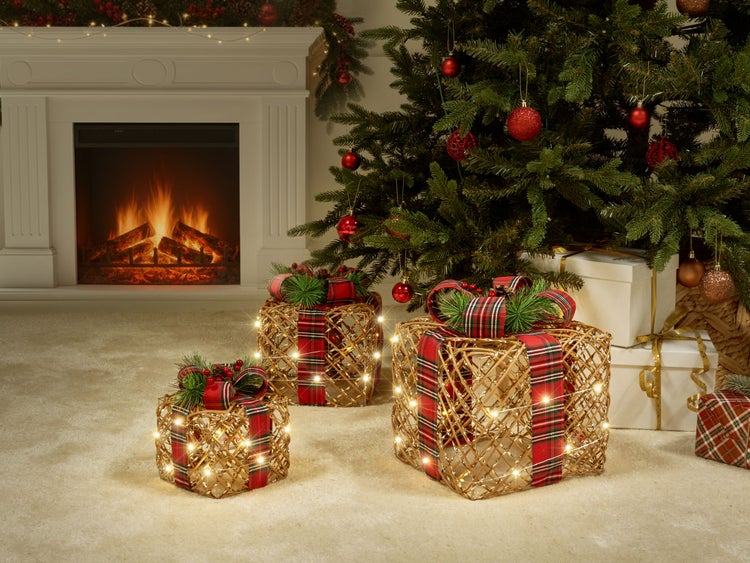 Beleuchtete LED-Geschenkkartons vor einem geschmückten Weihnachtsbaum und einem weißen Kamin.