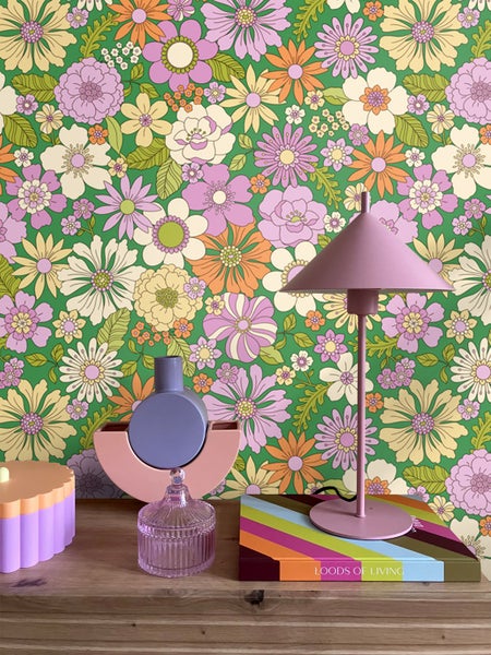 Dekorative Gegenstände auf einem Holztisch vor einer floralen Tapete