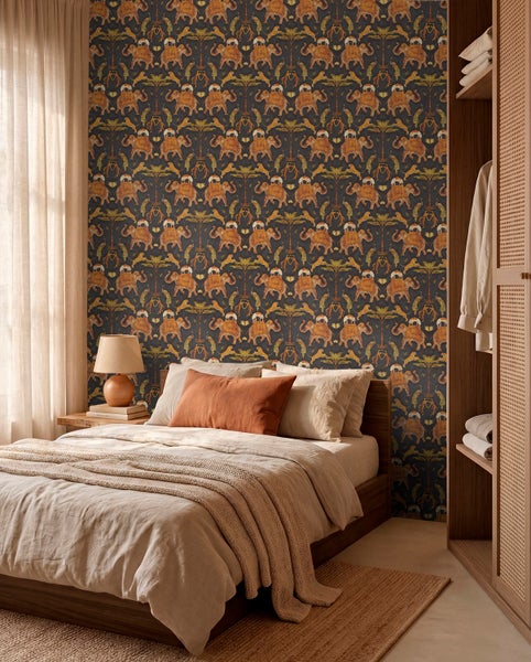 Vliestapete mit Elefanten-, Tiger- und Palmenmuster im Dschungel-Stil in einem Schlafzimmer mit Holzmöbeln und hellen Textilien.
