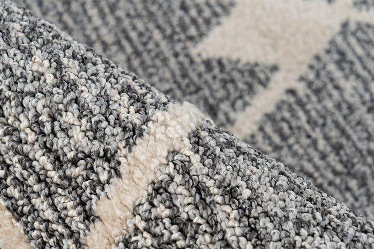 Nahaufnahme eines grau-beigen Teppichs mit Schlingenflor und geometrischem Muster.