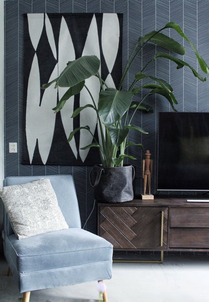 Wohnzimmer-Szene mit Sessel, Zimmerpflanze und dekorativer Wandgestaltung