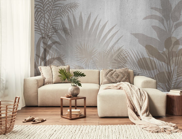 Wohnzimmer mit Sofa, Kissen, Tisch, Dekoration und Fototapete mit Pflanzenmotiven.