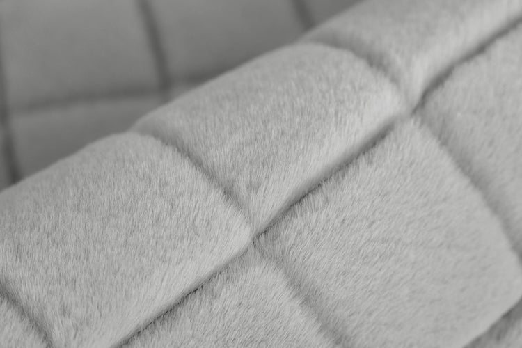 Detailansicht eines weichen Kunstfellstoffs mit gestepptem Karomuster.