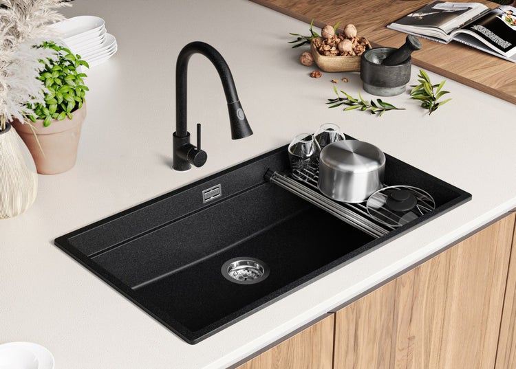 Schwarze Küchenspüle mit Wasserhahn und Abtropfgestell auf einer Küchentheke.