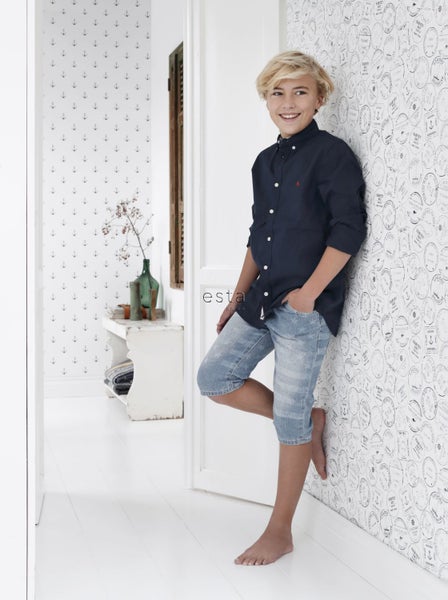 Szene mit einem Jungen in einem Flur mit Motivtapete und einem dekorativen Beistelltisch.