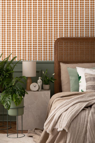 Schlafzimmer mit gemusterten Tapeten, Bett mit Kopfteil aus Rattan, Nachttisch und Pflanzen