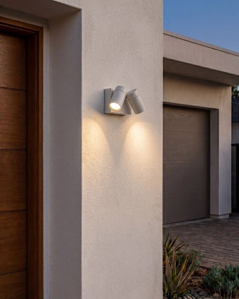 Moderne zweiflammige Außenwandleuchte mit warmweißem Licht an einer Hausfassade im Eingangsbereich.