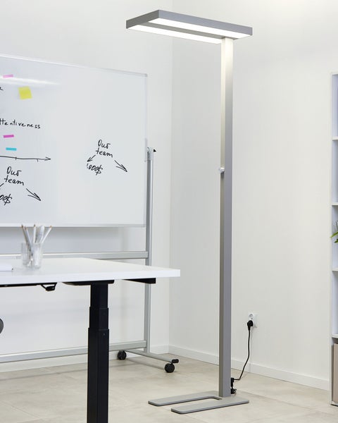 Stehleuchte aus Metall im Büro neben Schreibtisch und Whiteboard