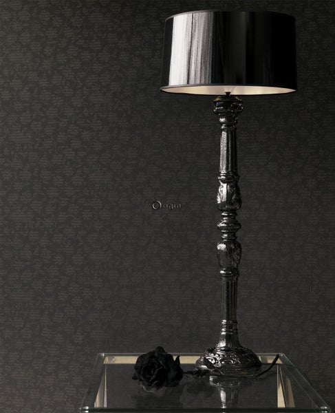 Dekorative Stehlampe auf Glasablage vor gemusterter Tapete