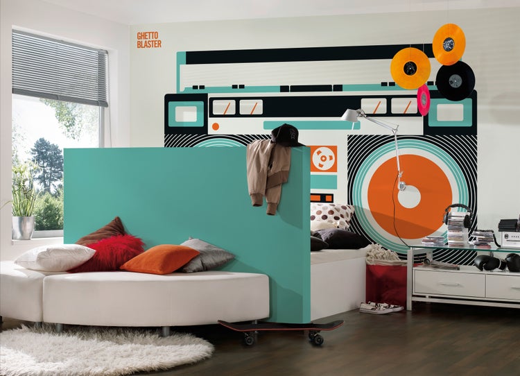 Modernes Zimmer mit Ghetto-Blaster-Fototapete, türkiser Trennwand, weißem Sofa mit bunten Kissen und einem Skateboard auf dem Boden.