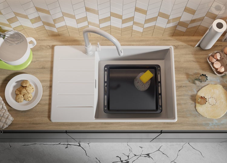 Spüle mit Backblech, Schwamm und verschiedenen Utensilien zum Backen auf einer Arbeitsplatte