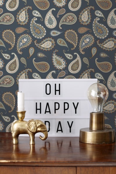 Dekorative Szene mit gemusterter Tapete, Leuchtkasten mit dem Schriftzug Oh Happy Day, Kerzenhalter in Elefantenform und Glühbirnenlampe.
