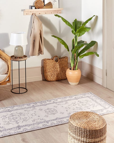 Dekoratives Zimmer mit Teppich, Zimmerpflanze und Flechtkorb