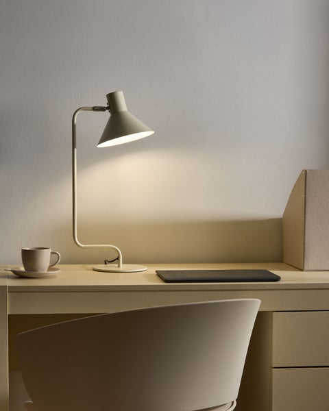 Minimalistische beige Tischleuchte auf einem Schreibtisch mit Grafiktablett und Tasse in einem ordentlichen Arbeitsbereich.
