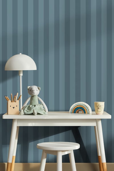 Kinderzimmer mit gestreifter Tapete, Schreibtisch, Lampe, Stuhl und Spielzeugdekoration