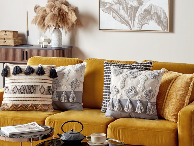 Wohnzimmer mit gelbem Sofa und dekorativen Kissen mit Quasten