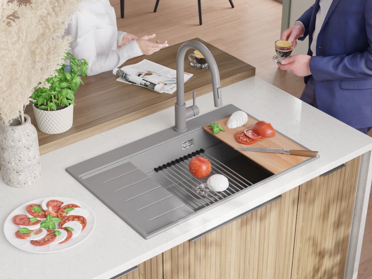 Küchenszene mit Spüle, Armatur, Schneidebrett, Zutaten und Personen im Hintergrund