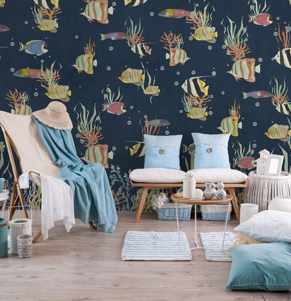 Dekoratives Zimmer mit Strandstuhl, Bank und Korbmöbeln vor einer Wandtapete mit Fischmotiven