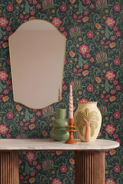 Wandgestaltung mit floraler Tapete oben und Wandtäfelung unten, einem kleinen Polsterhocker und dekorativen Hüten.