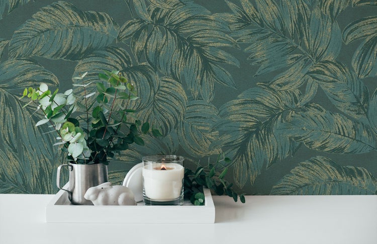 Dekoratives Arrangement mit einer Kerze, einer Pflanze und einer Hasenfigur vor einer grünen Blättertapete