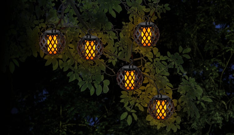 Dekorative Gartenleuchten mit Flammeneffekt hängen an einem Baum