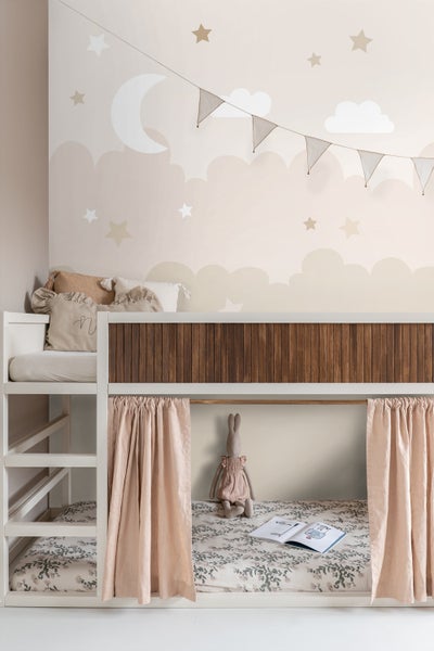 Blick auf ein Kinderzimmer mit einem Etagenbett, verziert mit Vorhängen, Kissen und einer Stoffpuppe.