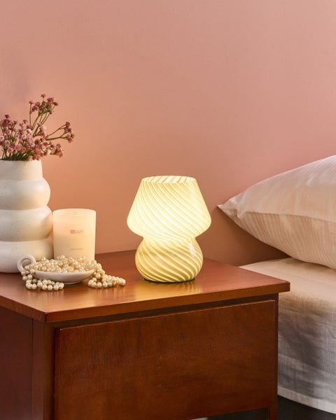 Szene mit Nachttisch, Lampe, Blumenvase, Kerze und Perlenkette