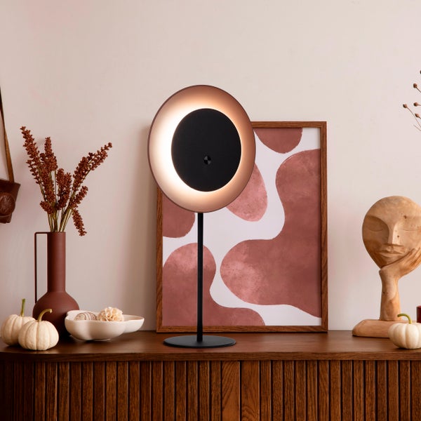 Dekoratives Interieur mit Leuchte, Bild und Holzskulptur auf einem Schrank