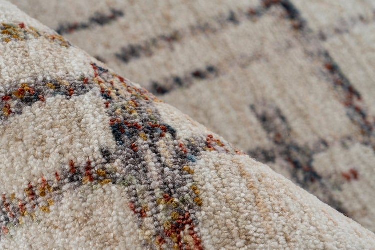 Nahaufnahme der Textur eines Teppichs mit weichem Flor und abstraktem, mehrfarbigem Muster.