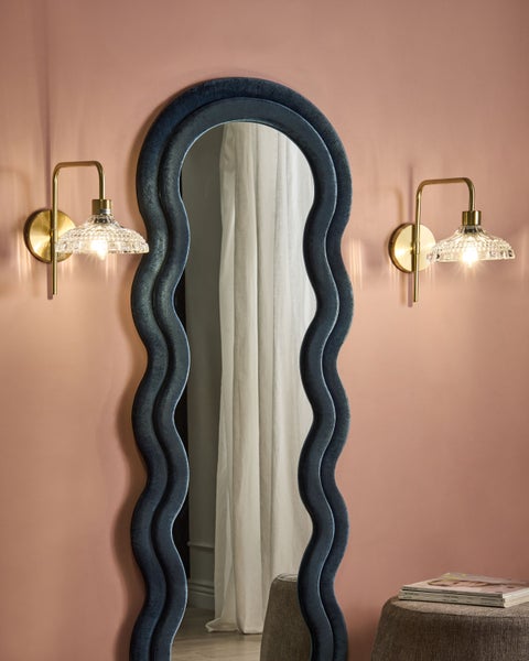 Innenraum mit einem gewellten Spiegel und zwei Wandleuchten
